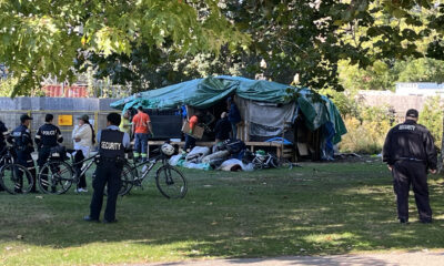 Security personnel are present as City of Toronto workers work to remove an encampment at Allan Gardens