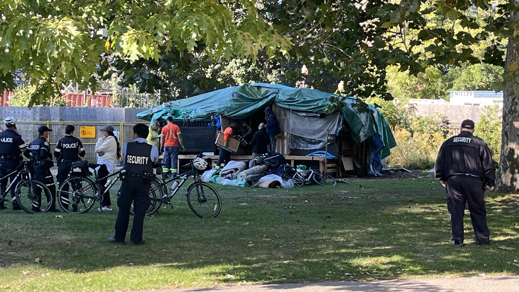 Security personnel are present as City of Toronto workers work to remove an encampment at Allan Gardens