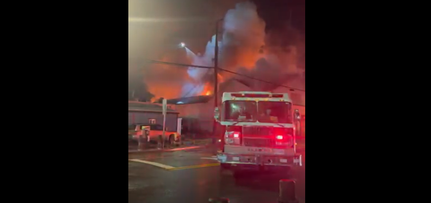 Flames can be seen as fire crews battle a fire at the Super Grocer and Pharmacy in the city's Steveston neighbourhood Friday evening.