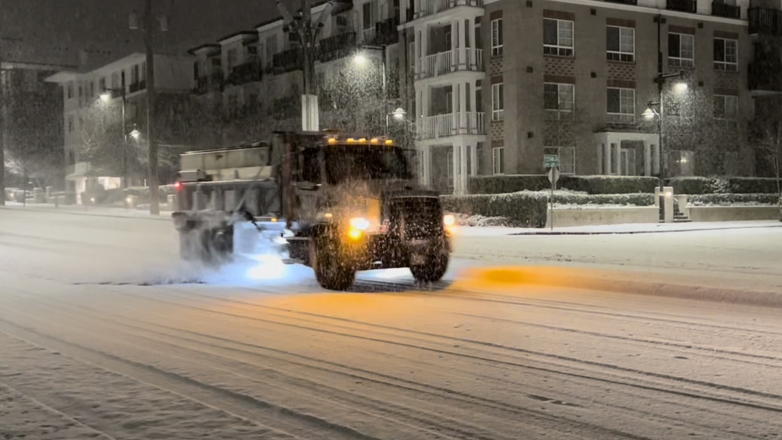 A snow plow drives down a street in Coquitlam