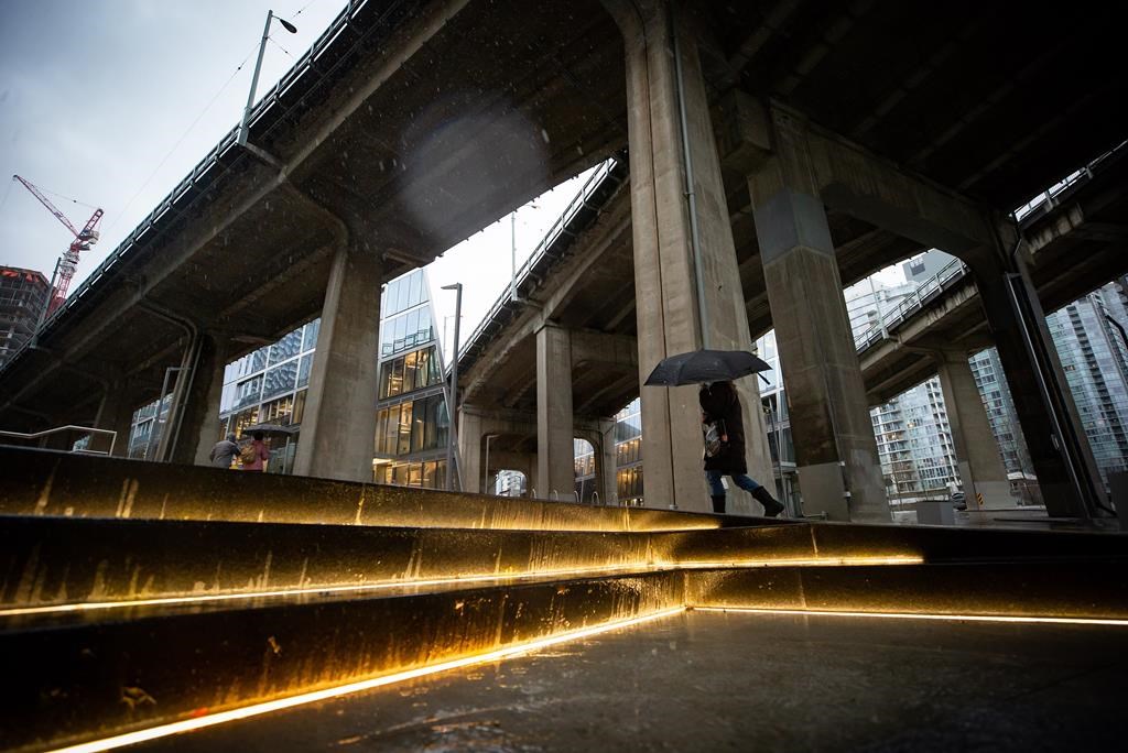 A person carries an umbrella as heavy rain falls in Vancouver, B.C., Tuesday, Jan. 5, 2021. Balmy weather and a series of rainstorms forecast for British Columbia’s South Coast have set off flood advisories for rivers, streams and low-lying areas.