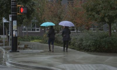 Two people walking with umbrellas in the Vancouver while it is raining.