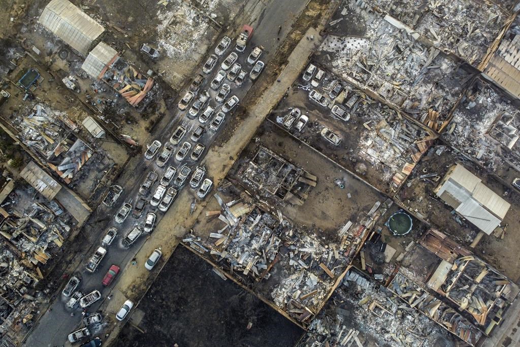 Burnt cars lie on a street after a forest fire reached Villa Independencia neighborhood in Vina del Mar, Chile, Saturday, Feb. 3, 2024.