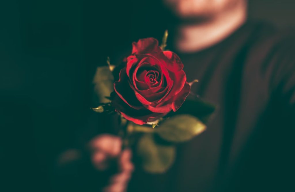 A man is holding a rose in this image.