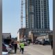 A crane is seen collapsed against a building in Kelowna as people look on from a distance