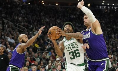 Boston Celtics' Marcus Smart (36) drives to the basket between Milwaukee Bucks' Jevon Carter, left, and Brook Lopez, right, during the first half of an NBA basketball game Thursday, March 30, 2023, in Milwaukee