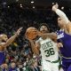 Boston Celtics' Marcus Smart (36) drives to the basket between Milwaukee Bucks' Jevon Carter, left, and Brook Lopez, right, during the first half of an NBA basketball game Thursday, March 30, 2023, in Milwaukee