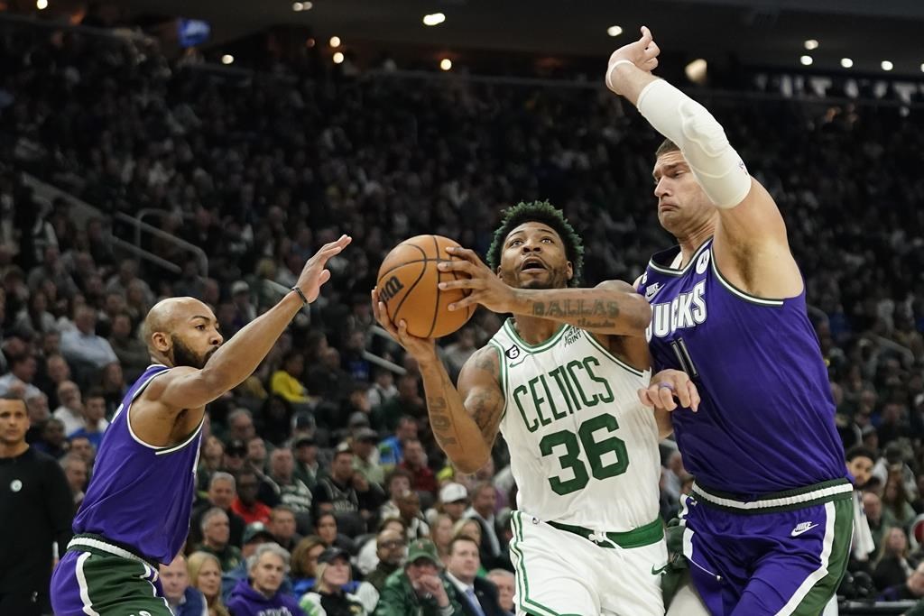 Boston Celtics' Marcus Smart (36) drives to the basket between Milwaukee Bucks' Jevon Carter, left, and Brook Lopez, right, during the first half of an NBA basketball game Thursday, March 30, 2023, in Milwaukee