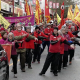 Image of Lunar New Year Parade in Vancouver Chinatown. People dressed in red with Lunar New Year signs stand in line at the parade.