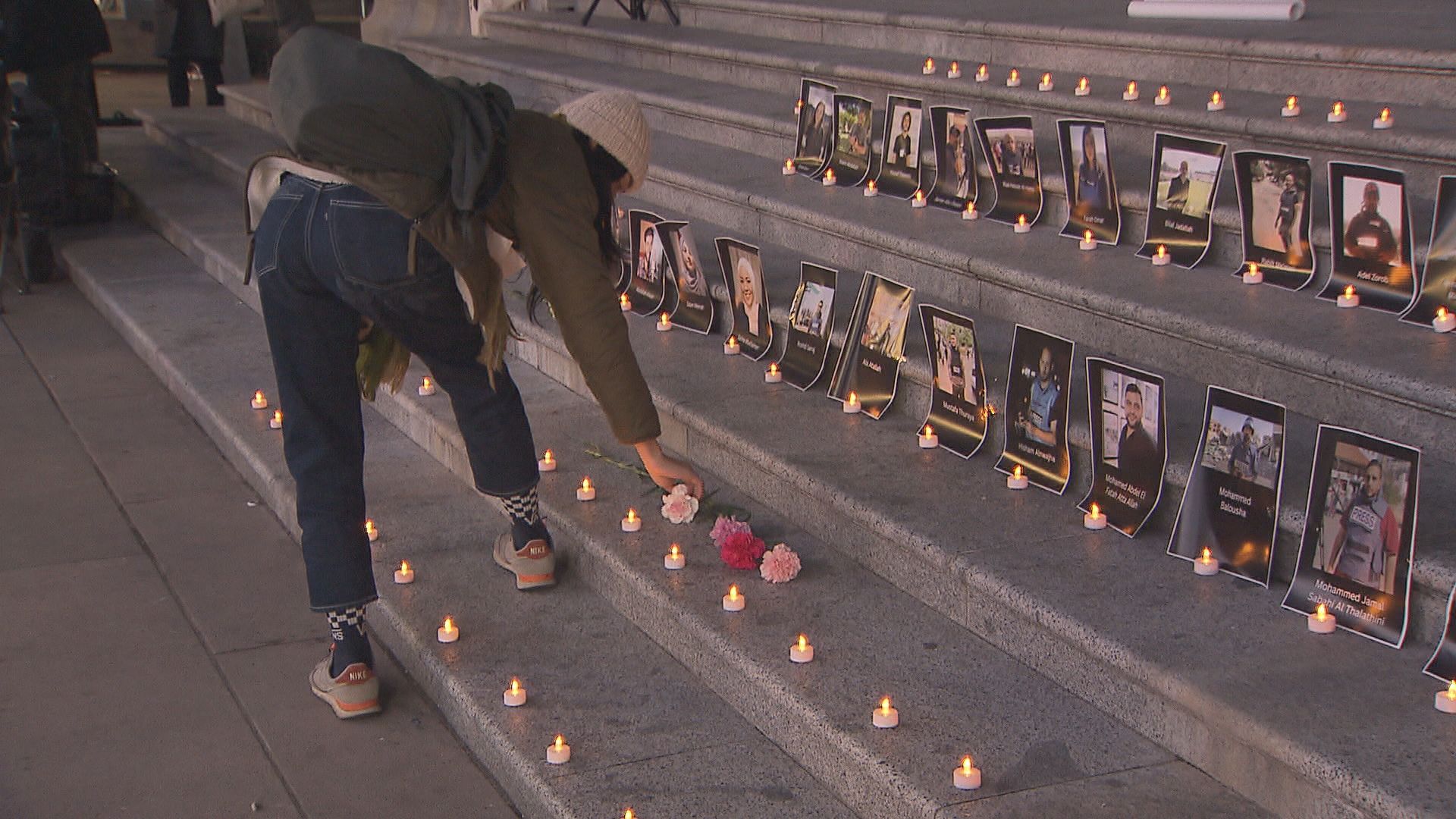 A person places a flower on the steps of the Vancouver Art Gallery