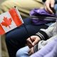 A new Canadian holds a flag as she takes part in a citizenship ceremony on Parliament Hill in Ottawa on April 17, 2019, to mark the 37th anniversary of the Canadian Charter of Rights and Freedoms