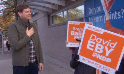 David eby speaks with people holding electoral signs