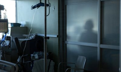 A health-care worker is silhouetted behind a glass panel at a hospital in Sarnia