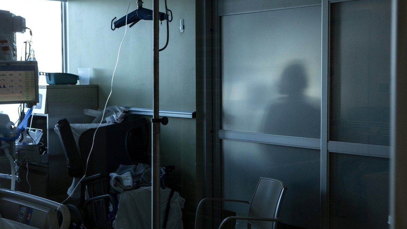 A health-care worker is silhouetted behind a glass panel at a hospital in Sarnia