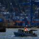 A water taxi travels on the Fraser River past cargo containers stacked at Fraser Surrey Docks below houses on a hill, in Surrey, B.C., on Monday, November 4, 2024. Business groups say the work stoppage at B.C. ports is the latest in a run of supply chain disruptions affecting Canadian companies and the country's economy.THE CANADIAN PRESS/Darryl Dyck