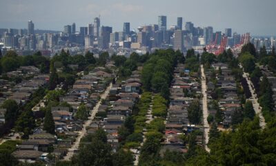 The downtown Vancouver skyline is seen in the distance beyond houses in Burnaby, B.C., on Wednesday, July 12, 2023. (THE CANADIAN PRESS/Darryl Dyck)