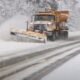 A snow plow is seen on a highway.