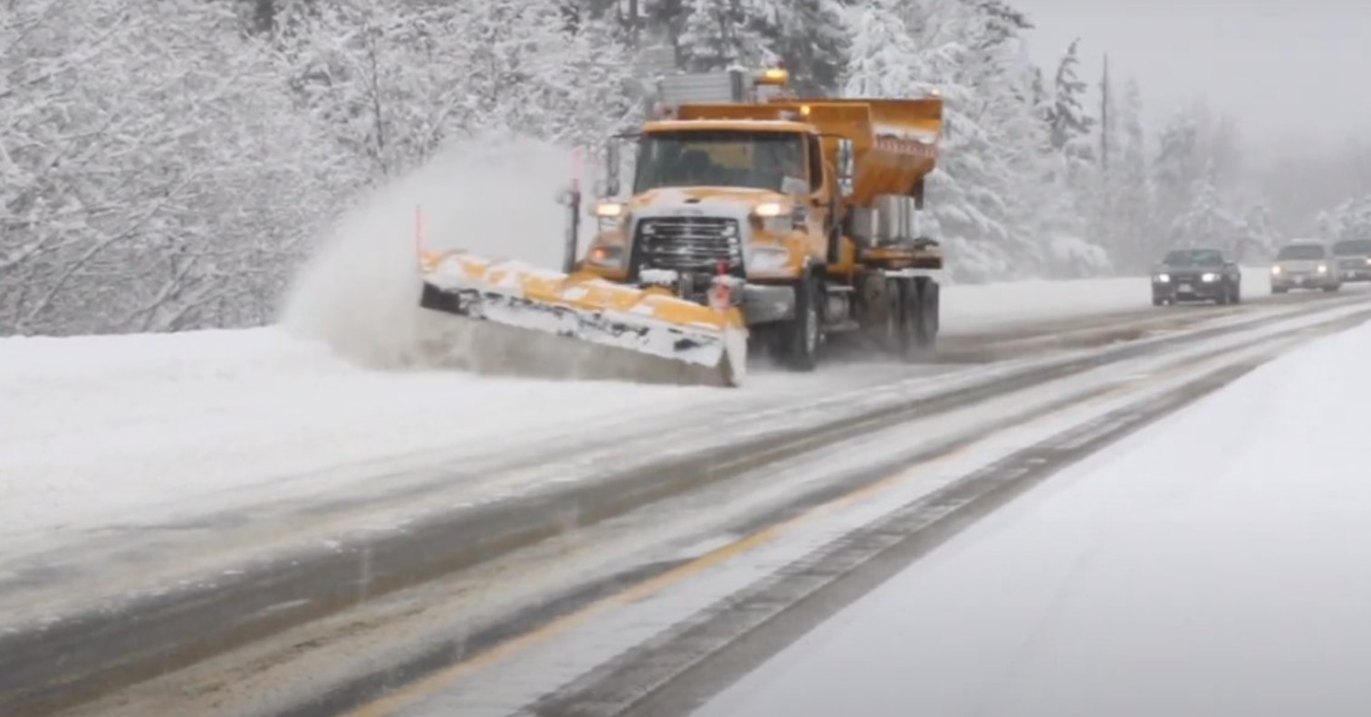 A snow plow is seen on a highway.