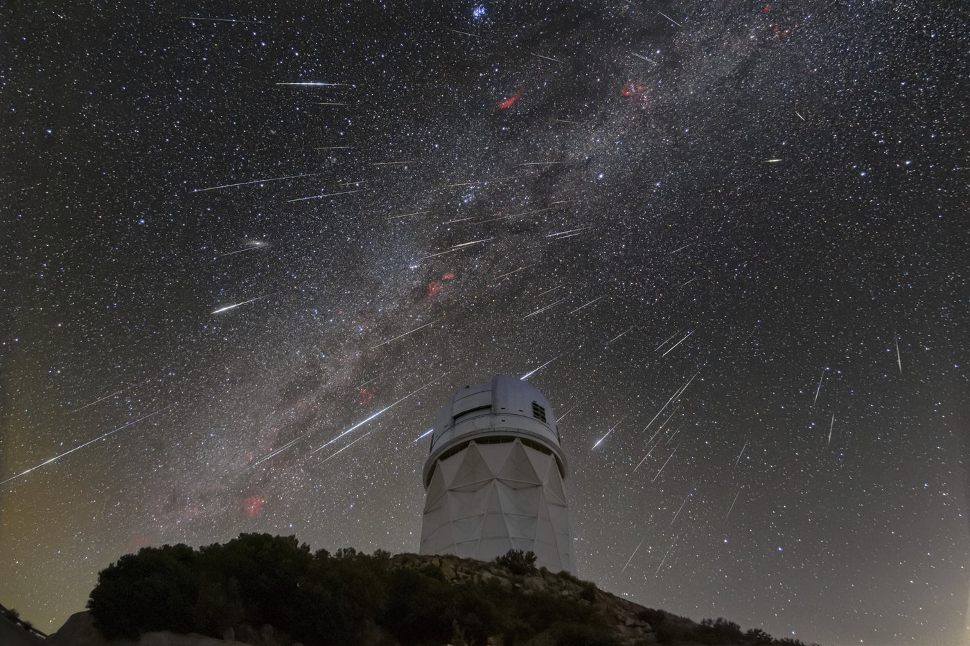 meteors from the Geminid meteor shower streak across the sky above the Nicholas U. Mayall Telescope