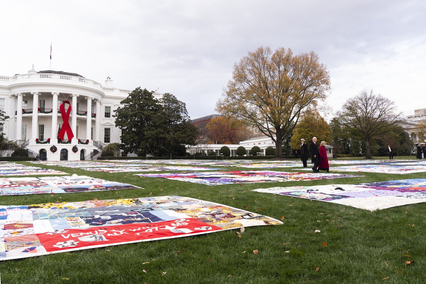 President Joe Biden and first lady Jill Biden walk between AIDS Memorial Quilts spread over the South Lawn of the White House during a ceremony to commemorate World AIDS Day with survivors, their families and advocates, Sunday, Dec. 1, 2024, in Washington.