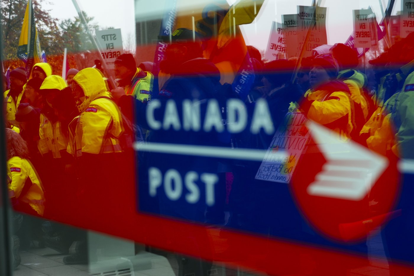 The strike by more than 55,000 Canada Post workers entered its 19th day as the Black Friday and Cyber Monday shopping weekend came to a close. Canada Post employees and supporters rally as they are reflected in a window at Canada Post headquarters in Ottawa, Thursday, Nov. 28, 2024.